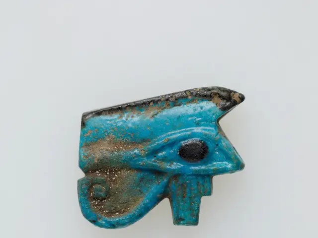 The image shows an ancient Egyptian faience amulet in the shape of an eye of Horus, which is blue...